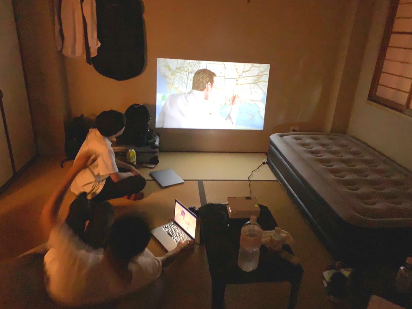 プロジェクターで映画を見る住人たち